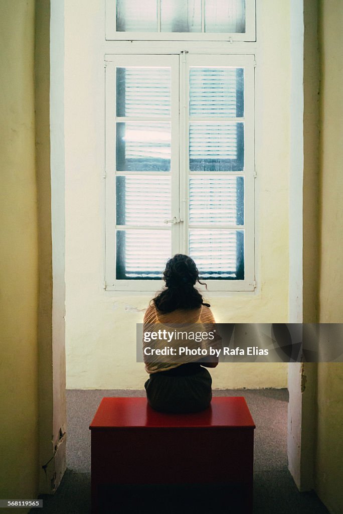 Woman sitting on bench in front of closed window