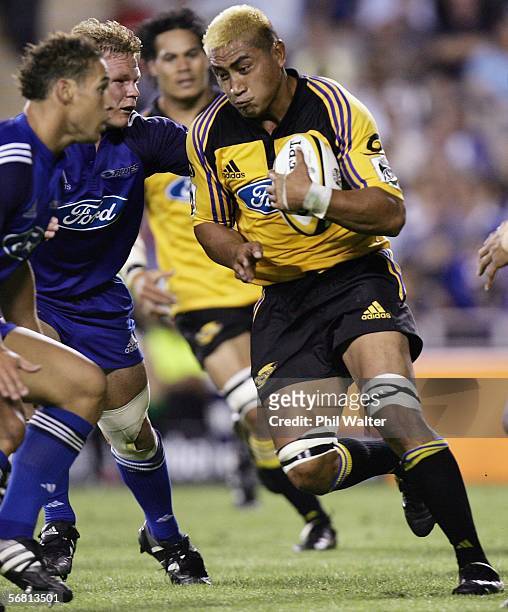 Jerry Collins of the Hurricanes runs into the tackle of Daniel Braid and Luke McAlister of the Blues during the round one Super 14 match between the...