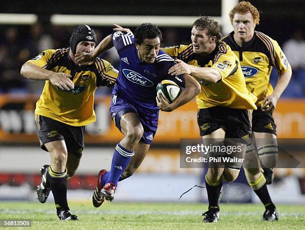 John Senio of the Blues is tackled by Andrew Hore and Jason Eaton of the Hurricanes during the round one Super 14 match between the Blues and the...