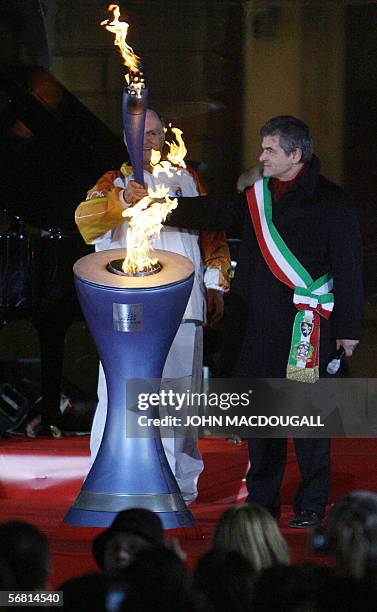 Former Italian Olympic champion Livio Berruti lights the Olympic flame as Turin's Mayor Sergio Chiamparino looks on during the penultimate Olympic...