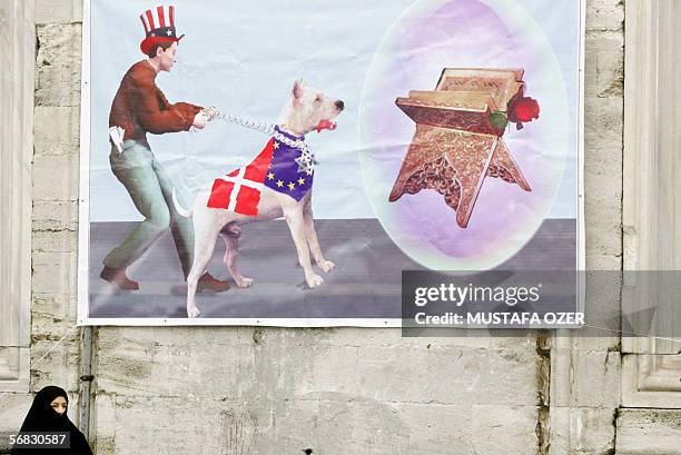 Turkish Islamic woman stands under a poster, showing Uncle Sam holding a dog wearing Danish and EU flag with Jewish star chain in front of the Koran,...