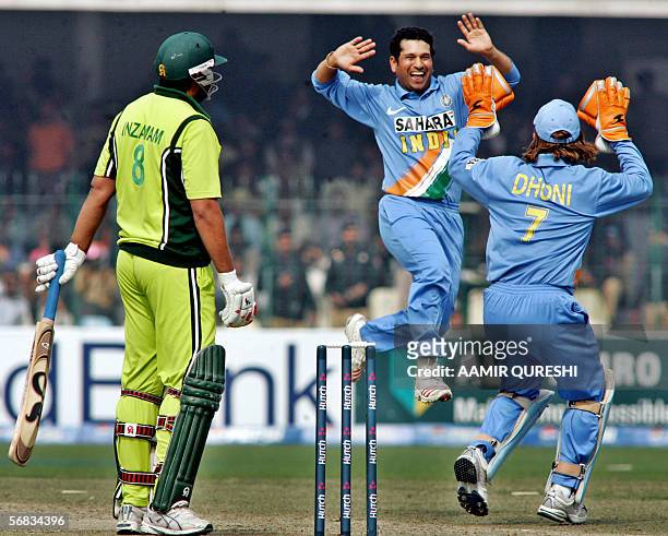 Indian cricketer Sachin Tendulkar leaps into the air as he celebrates with team wicketkeeper Mahendra Singh Dhoni after taking the wicket of...