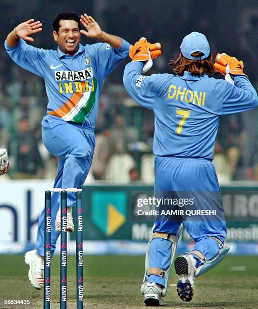 Indian cricketer Sachin Tendulkar leaps into the air as he celebrates with team wicketkeeper Mahendra Singh Dhoni after taking the wicket of unseen...