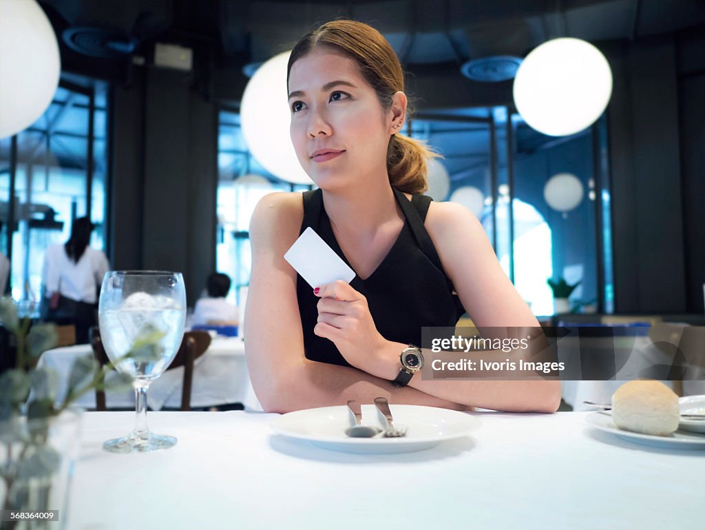 Asian women using a credit card in a restaurant.