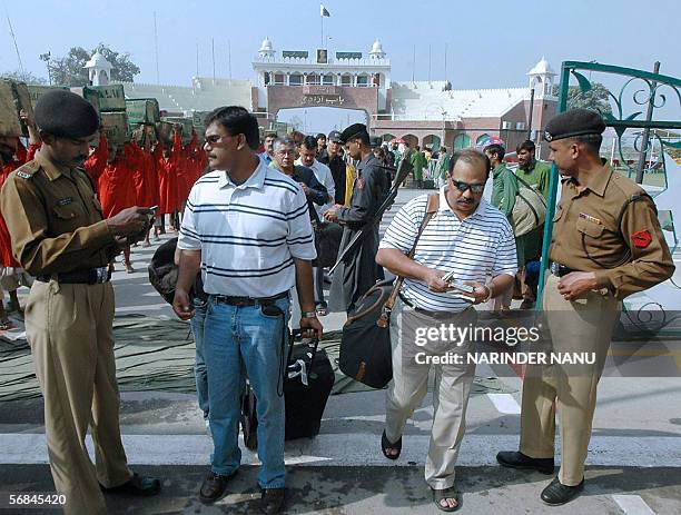 Indian cricket supporters have their passports checked by Indian and Pakistani border security personnel as they cross the India-Pakistan Border at...