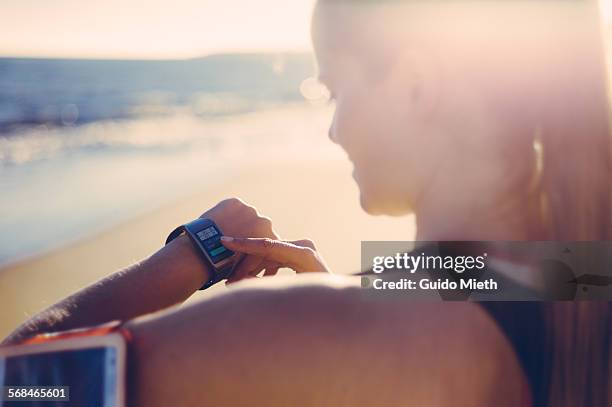 woman synchronizing smartwatch and mobile phone. - longeville sur mer stock pictures, royalty-free photos & images