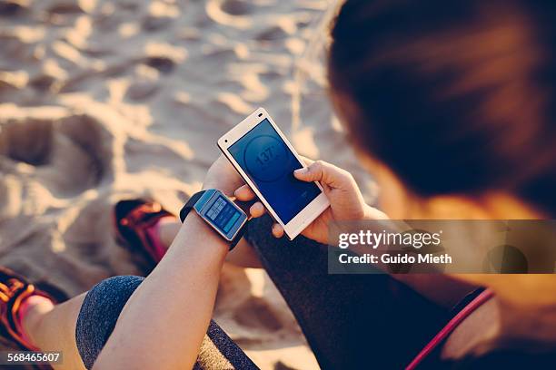 woman synchronizing smartwatch and mobile phone. - longeville sur mer stock pictures, royalty-free photos & images