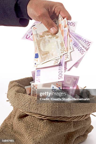 man taking money from sack - geld verheizen stock-fotos und bilder