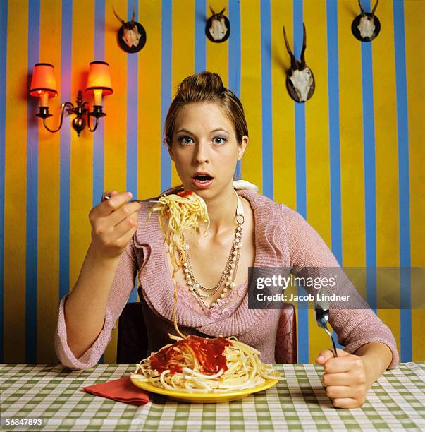 young woman eating spaghetti - rimpinzarsi foto e immagini stock