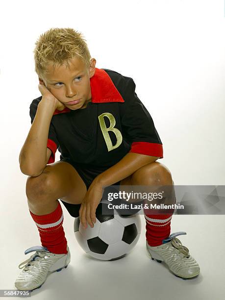 boy (8-11) sitting on soccer ball, looking to side - northern european descent stock pictures, royalty-free photos & images