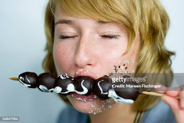 woman eating chocolate fruit spit, closed eyes - chocolate closed eyes stock-fotos und bilder