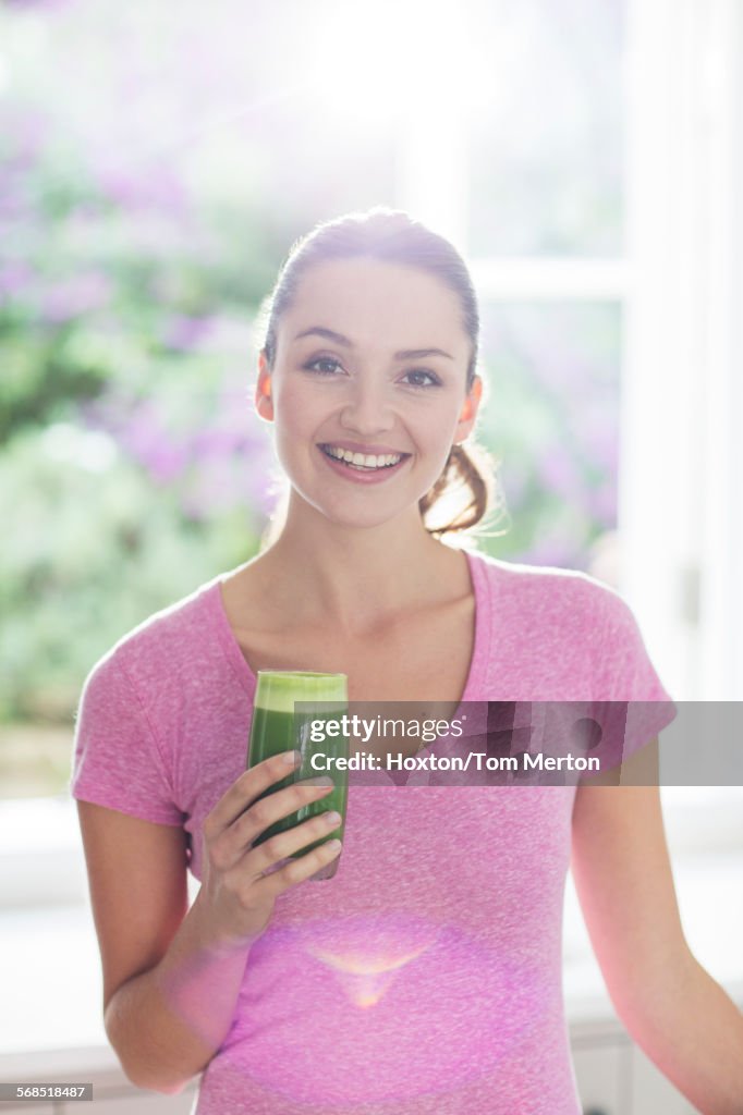 Portrait smiling woman drinking green smoothie