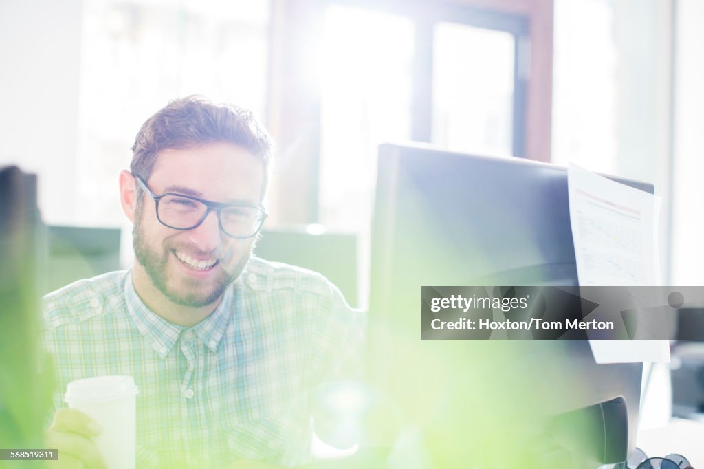 Portrait d’homme d’affaires créatif enthousiaste buvant du café à l’ordinateur