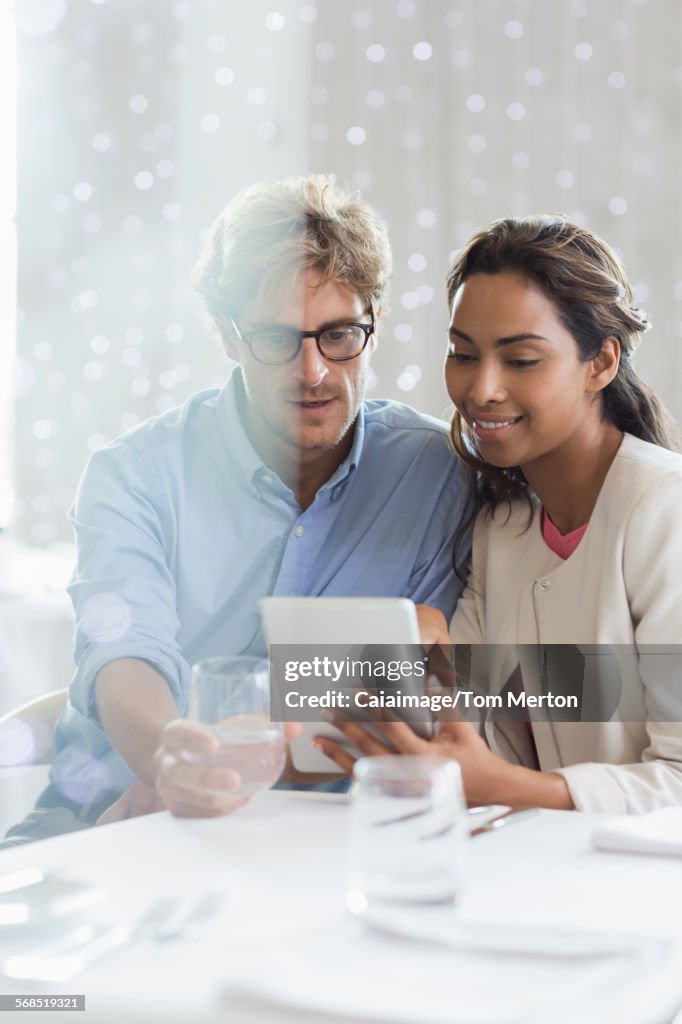 Couple using digital tablet at restaurant table