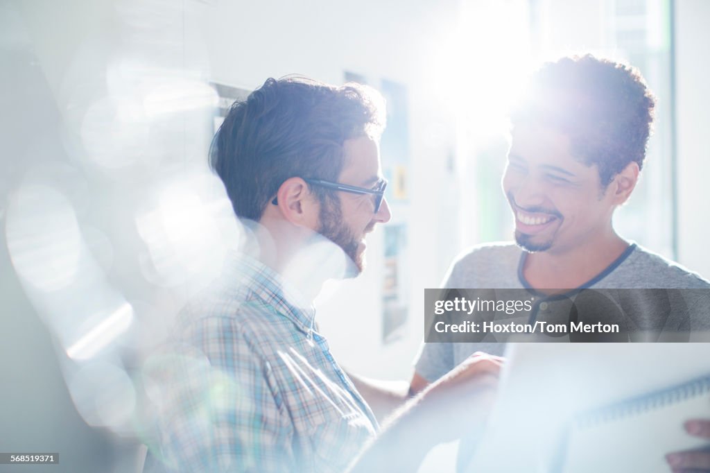 Smiling creative businessmen using digital tablet in sunny office