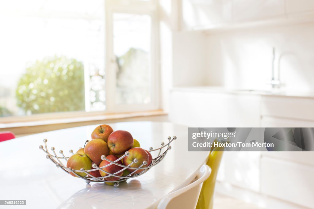 Pommes dans un panier en fil de fer sur une table de cuisine moderne