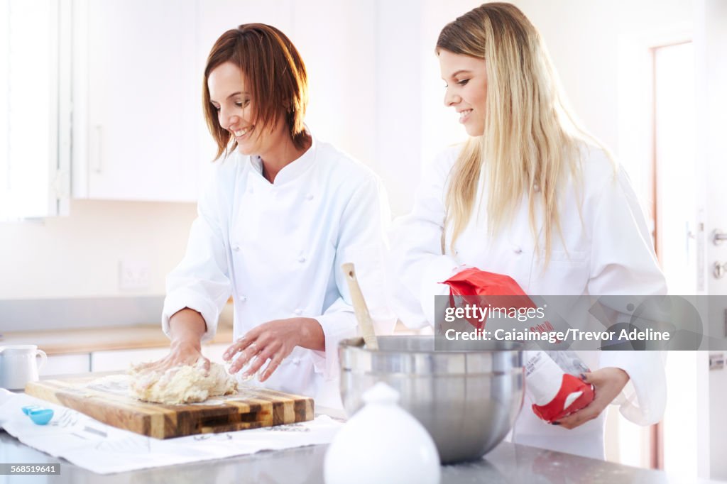 Chefs baking kneading dough on cutting board in kitchen