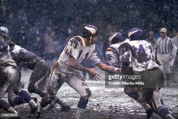 Quarterback Joe Kapp of the Minnesota Vikings hands of the ball to running back Dave Osborn as snow falls during a cold game against the Detroit...