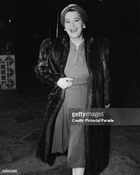 American actress, singer, and comedian Fanny Brice wears a turban and a fur coat as she arrives for a preview of the film 'The Cat and the Canary,'...
