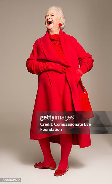 smiling senior woman wearing red coat - red coat stock-fotos und bilder