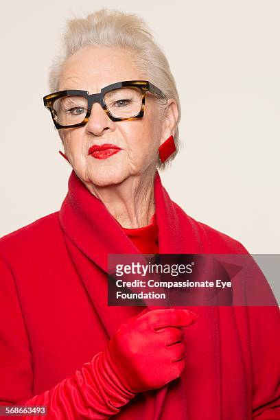 senior woman wearing glasses and red coat - red glove stock pictures, royalty-free photos & images