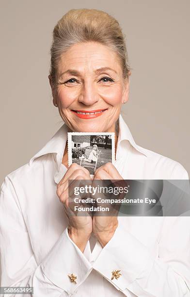 Senior woman holding photo of her younger self