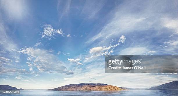 blue sky and clouds over water and land - maestosità foto e immagini stock