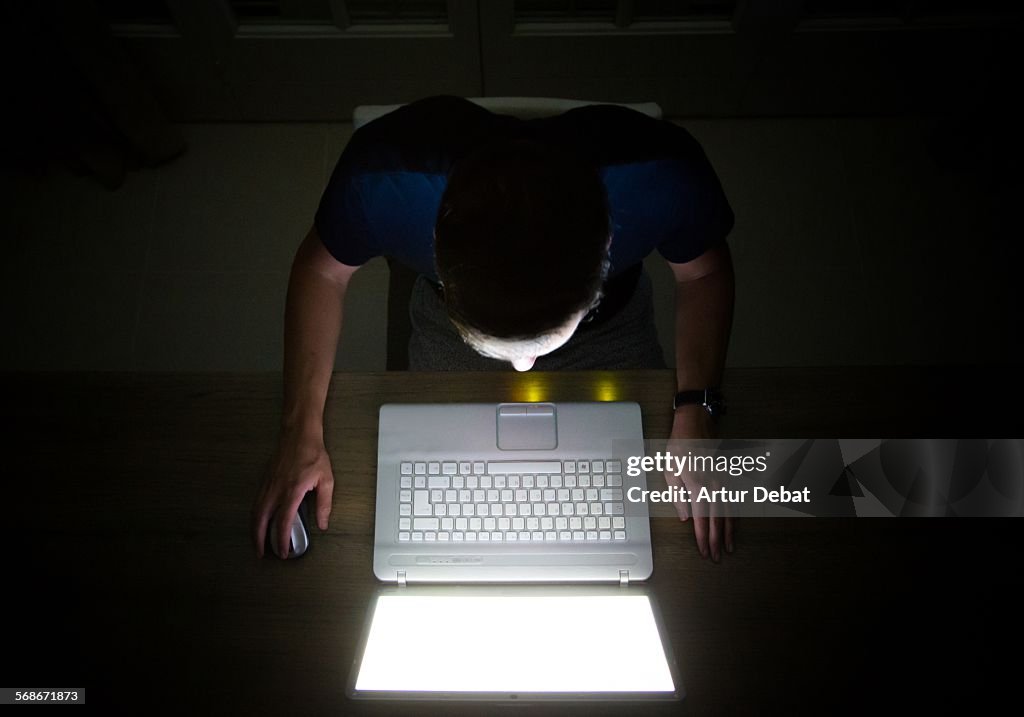 Overhead view of a man at dark night with laptop.