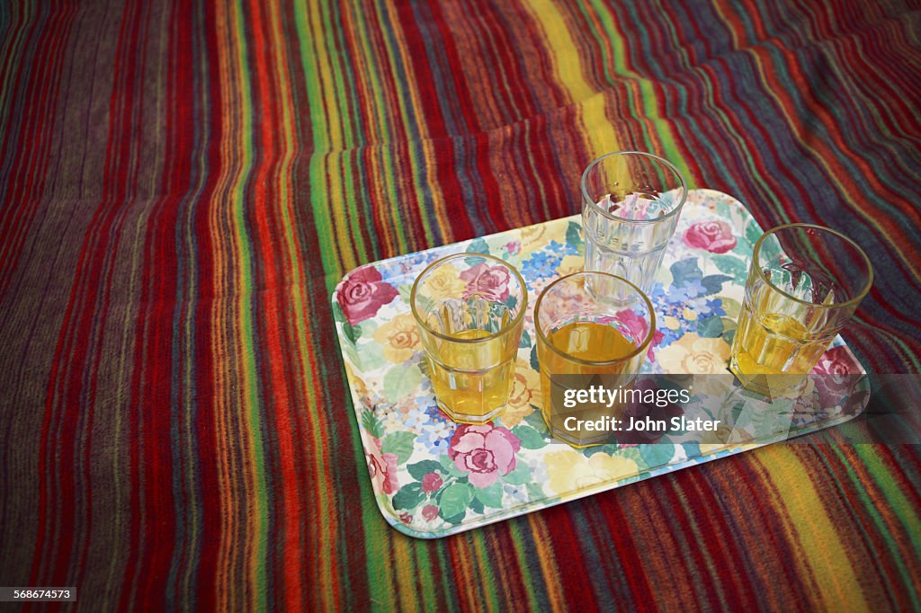 Plastic tumblers of juice on a tray and bed