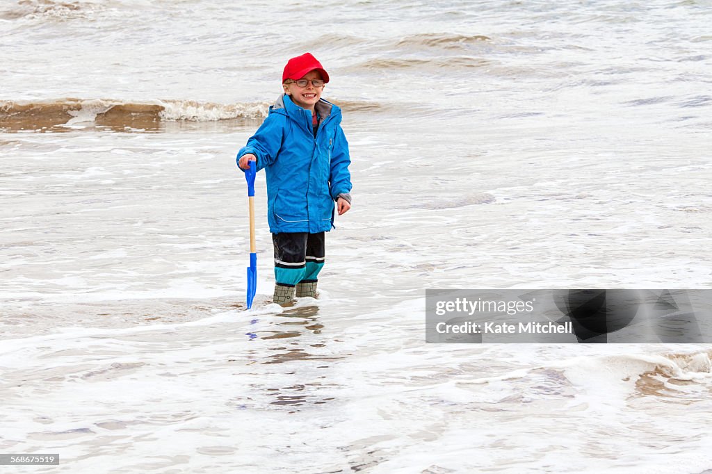 Young boy stood in the sea fully clothed