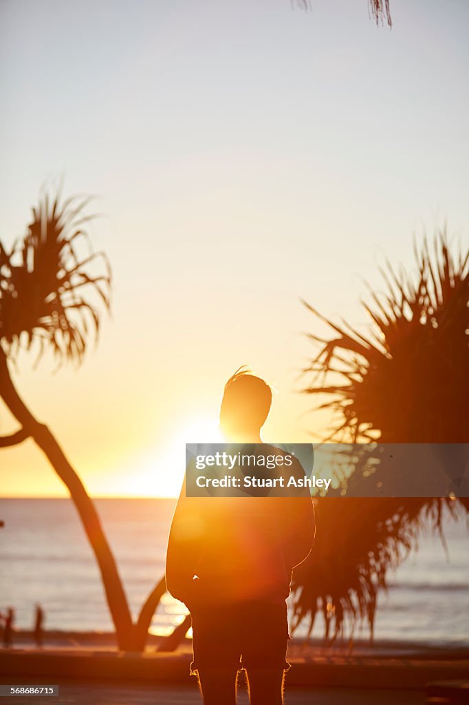 Male watches over sunrise ocean