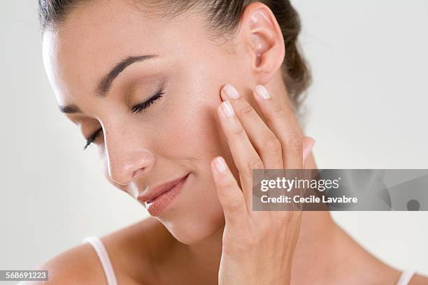 woman massaging her face with finger - beautification stock pictures, royalty-free photos & images