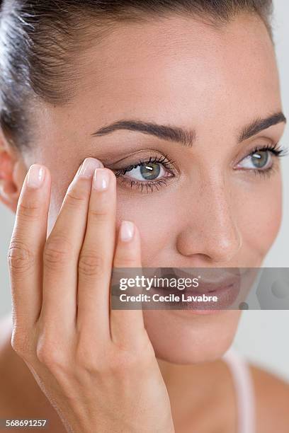 woman touching eye wrinkles with finger - forehead stock-fotos und bilder