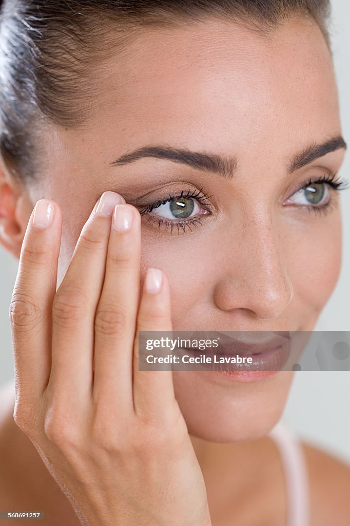 Woman touching eye wrinkles with finger