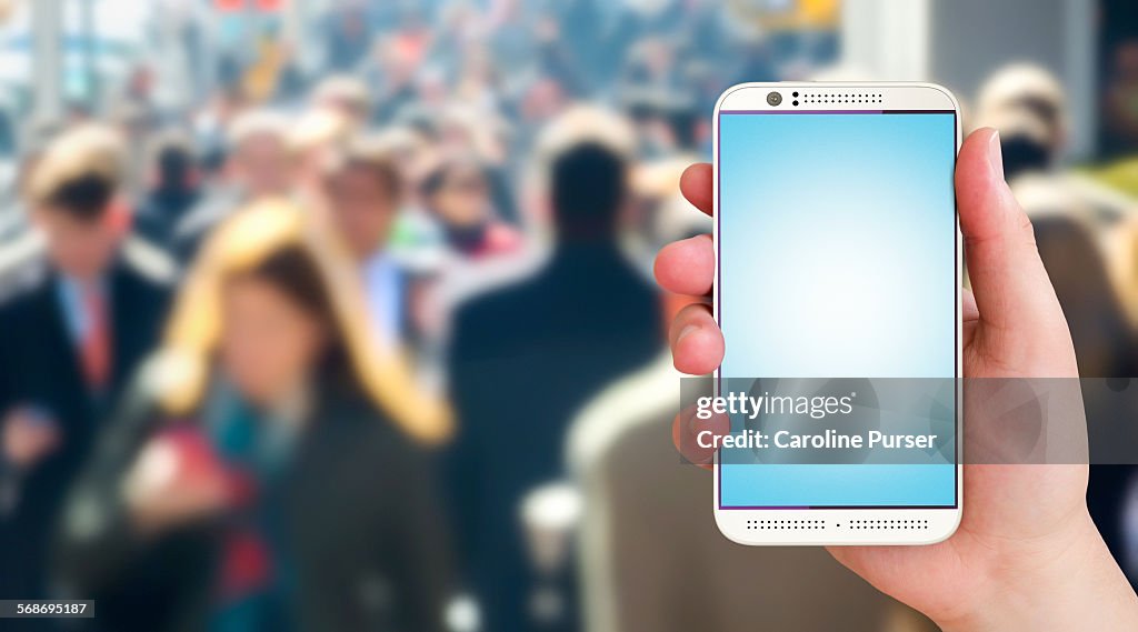 Closeup of mobile phone against crowd background