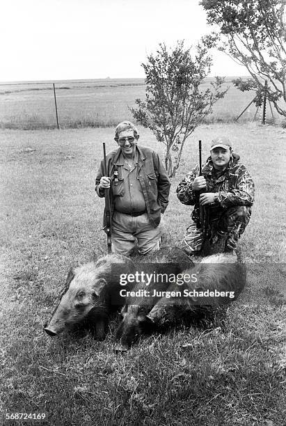 Farmers pose with their hunting trophies, three wild pigs in South Africa, 2005.