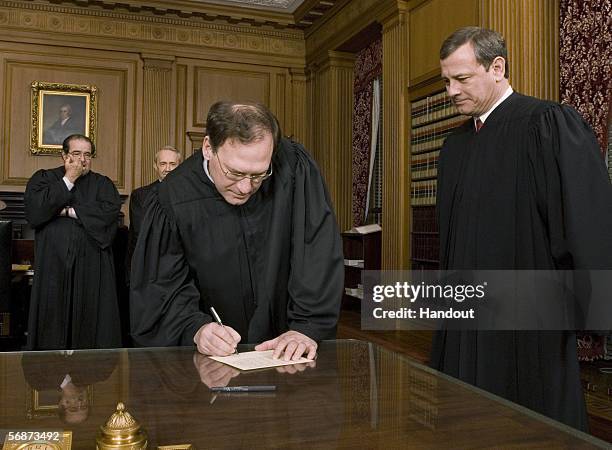 Justice Samuel A. Alito, Jr. Signs his oath card in the Justices' Conference Room as Chief Justice John G. Roberts, Jr. Looks on with Justices...