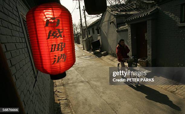 Sunshine lights up a lantern as a cyclist passes through one of Beijing's fast disappearing hutong's or courtyard houses, 18 February 2006. Beijing's...