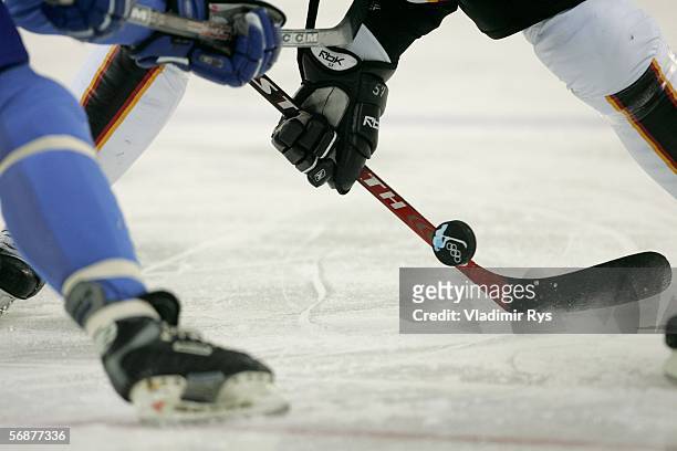 An Italian player fights for the puck with a German player during the men's ice hockey Preliminary Round Group A match between Italy and Germany...