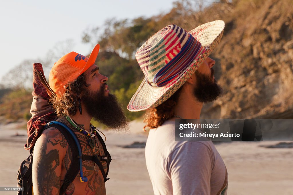 Two bearded travelers stroll along the beach