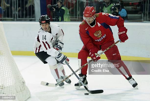 Alexei Yashin of Russia fights for the puck with Leonids Tambijevs of Latvia during the men's ice hockey Preliminary Round Group B match between...