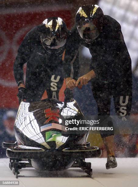 1of Todd Hays and Pavle Jovanovic push their bob at the start of the third run of the two-man bobsleigh event at the Turin 2006 Winter Olympics in...