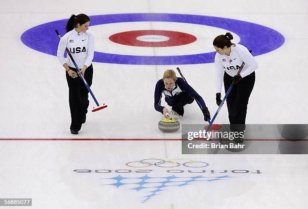 Cassie Johnson of the United States curls her stone to the right as Courtney George and Maureen Brunt prepare to sweep during a preliminary round of...