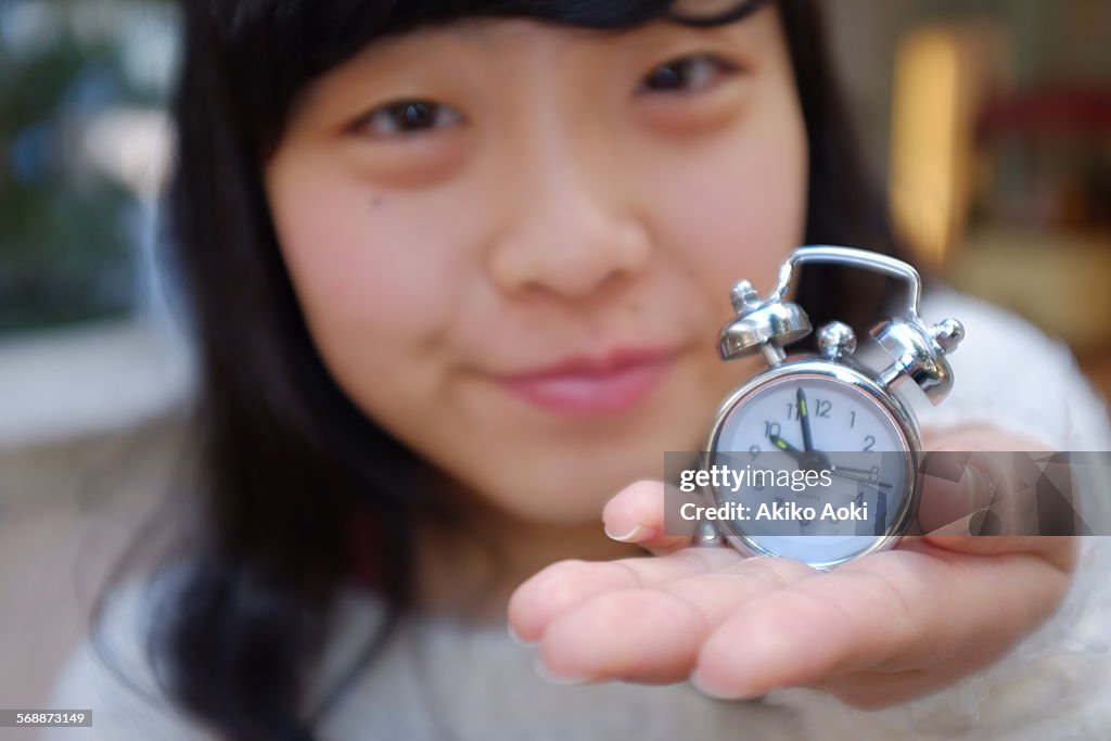 Girl and small alarm clock on her hand.