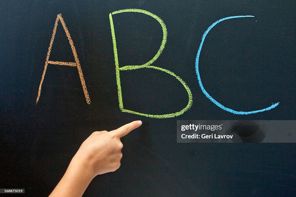 Person pointing to 'ABC' on a blackboard