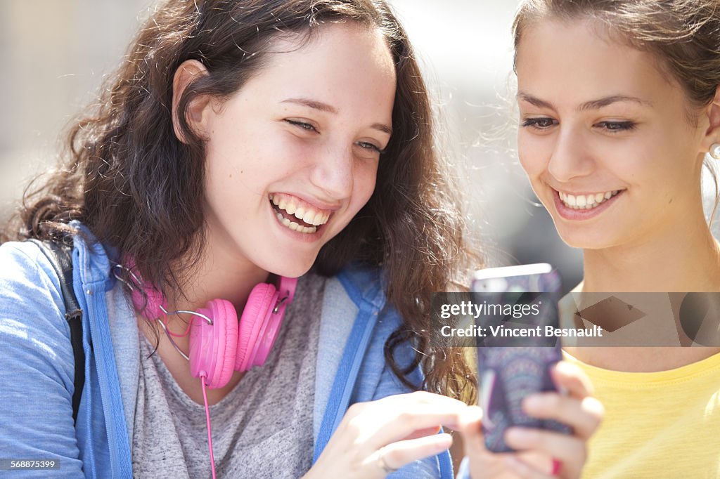 Two girls after school looking at mobile phone