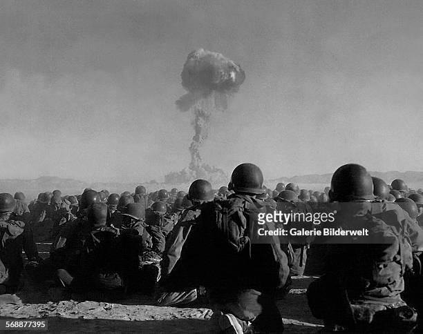 Troops of the U.S. Army 11th Airborne Division watch a plume of radioactive smoke rise after a blast at Yucca Flats during Operation Buster- Jangle...