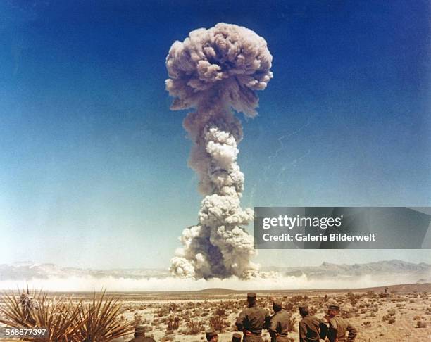 Troops of the U.S. Army 11th Airborne Division watch a plume of radioactive smoke rise after a blast at Yucca Flats during Operation Buster- Jangle...