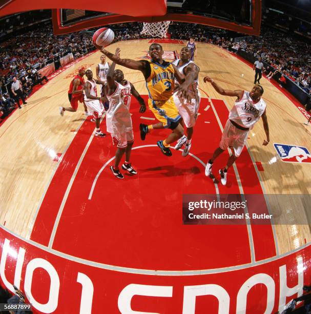 Chris Paul of the Rookie Team takes the ball to the basket against Luol Deng and Dwight Howard of the Sophomore Team during the T-Mobile Rookie...