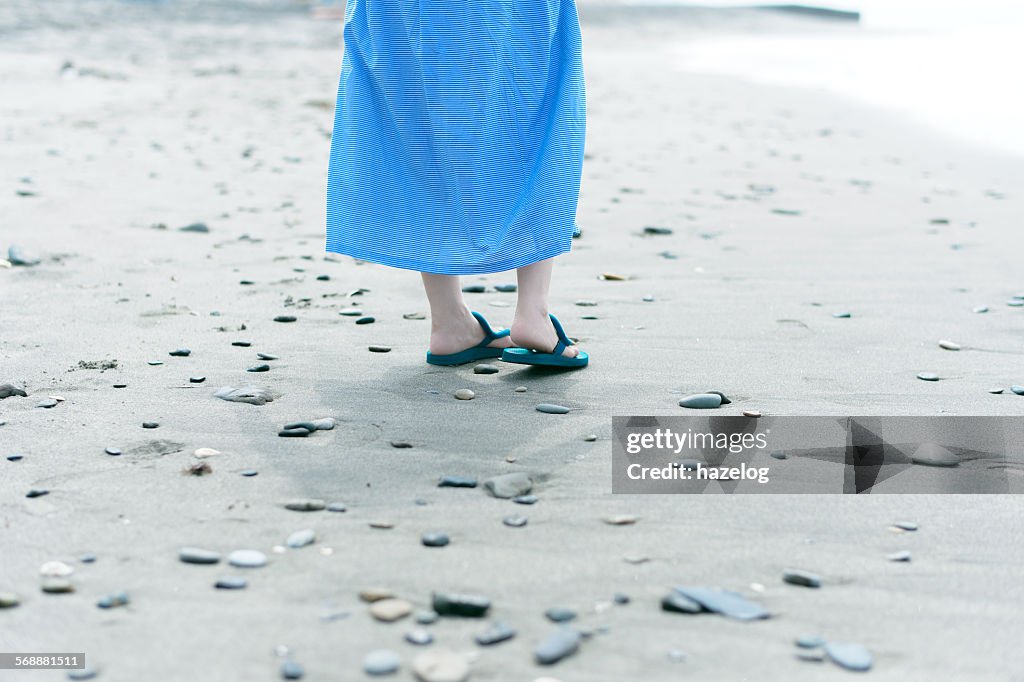 Woman wearing flip flops, walk on stone beach